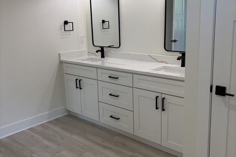 White double vanity with a quartz top and black fixtures, polished during an add-on visit