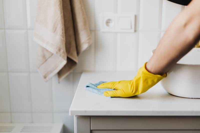 Gloved hand wiping down a counter during a routine clean
